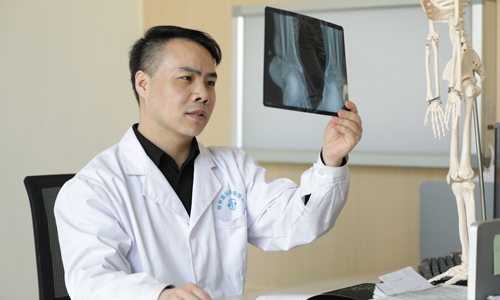 (图:焦琦主任研究患者膝关节处x光片,了解骨质受损情况) (图:焦琦主任研究患者膝关节处x光片,了解骨质受损情况)